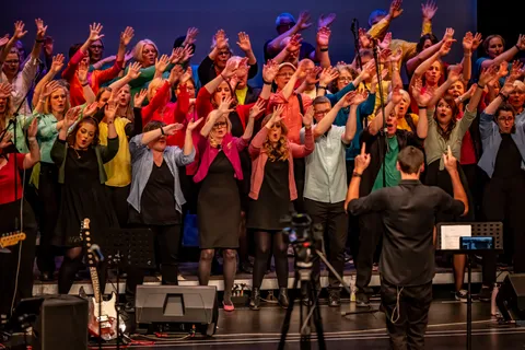 Der Chor colorsounds bei einer synchronen Choreografie, davor der Dirigent