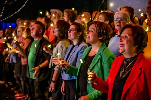 Sängerinnen und Sänger von colorsounds halten leuchtende LED-Lichter beim Konzert